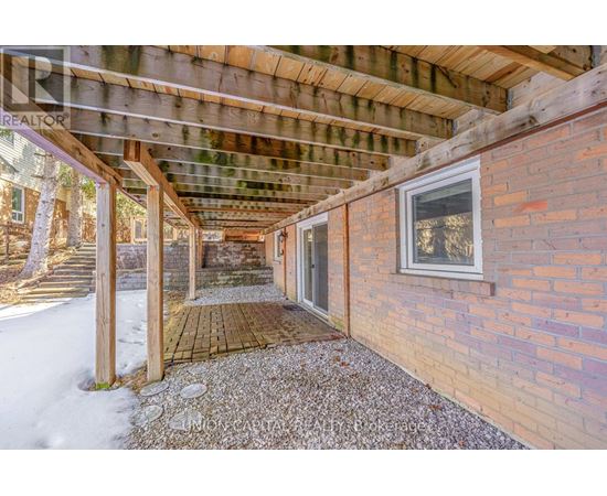 A wooden covered walkway leads to a house.