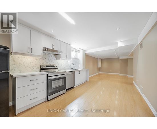 A kitchen with white cabinets and wooden floors.