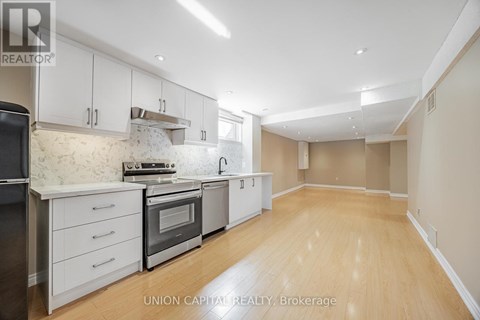 A kitchen with white cabinets and wooden floors.