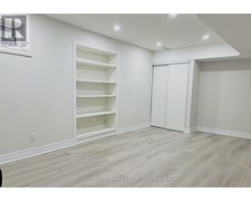 A room with white walls and wooden flooring, with a sign that reads "REALTOR" on the wall.