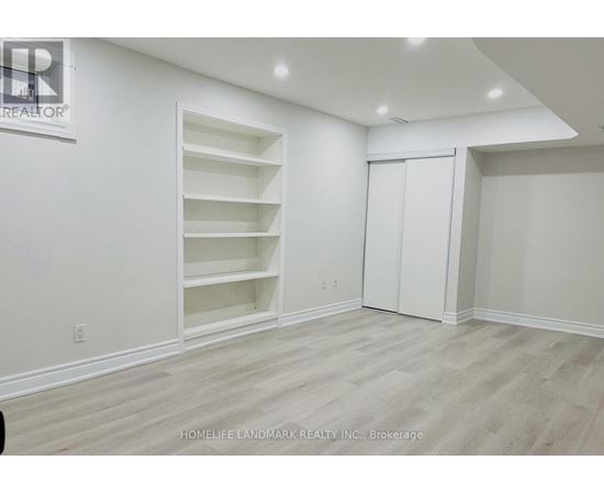 A room with white walls and wooden flooring, with a sign that reads "REALTOR" on the wall.