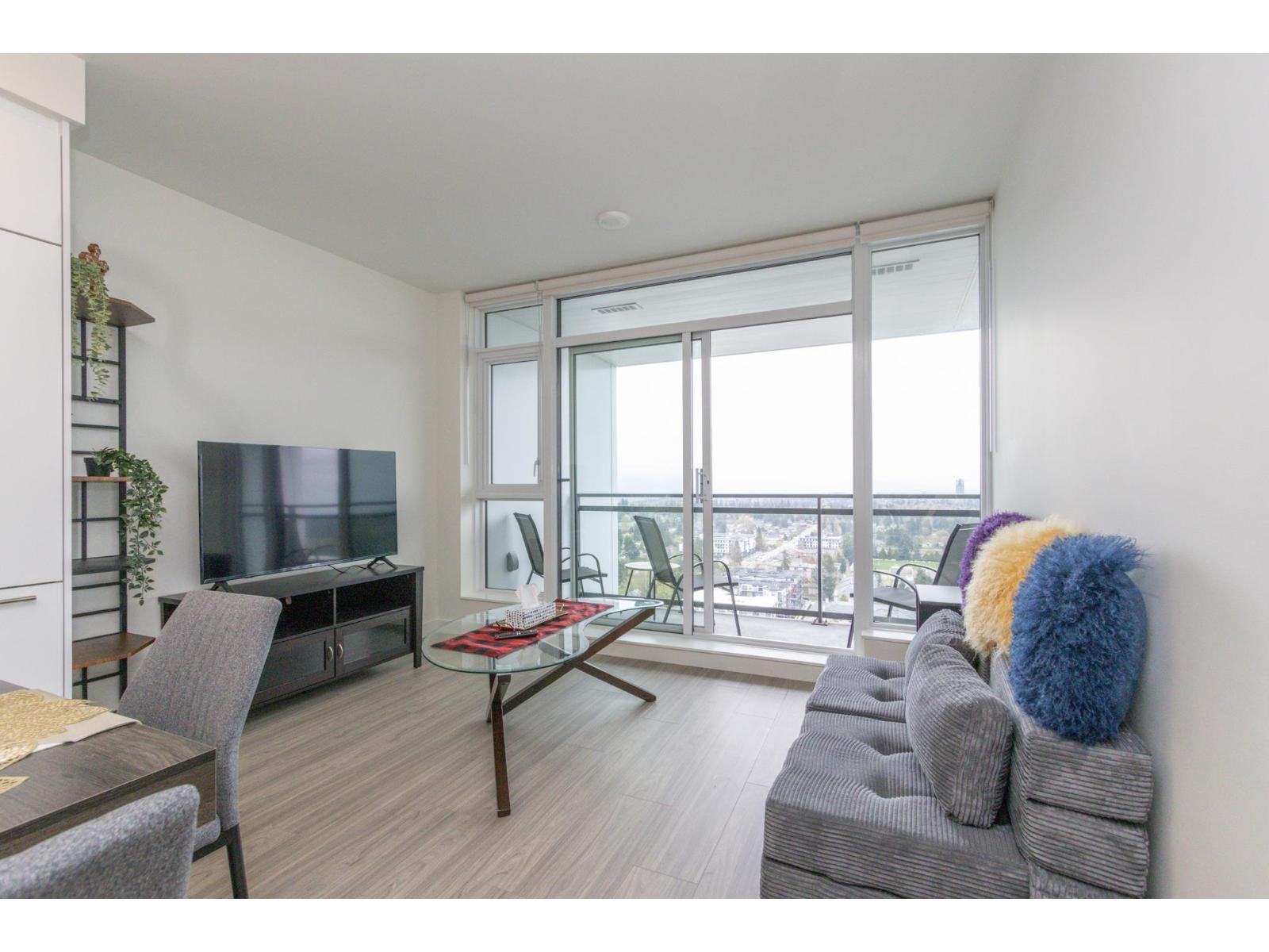 A living room with a grey couch and a glass table.