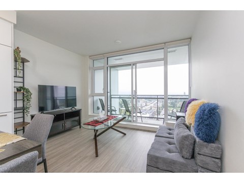 A living room with a grey couch and a glass table.