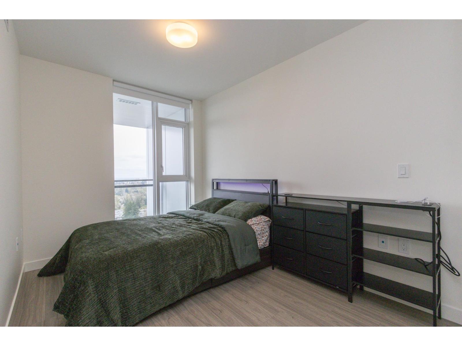 A bedroom with a bed, nightstand, and window.