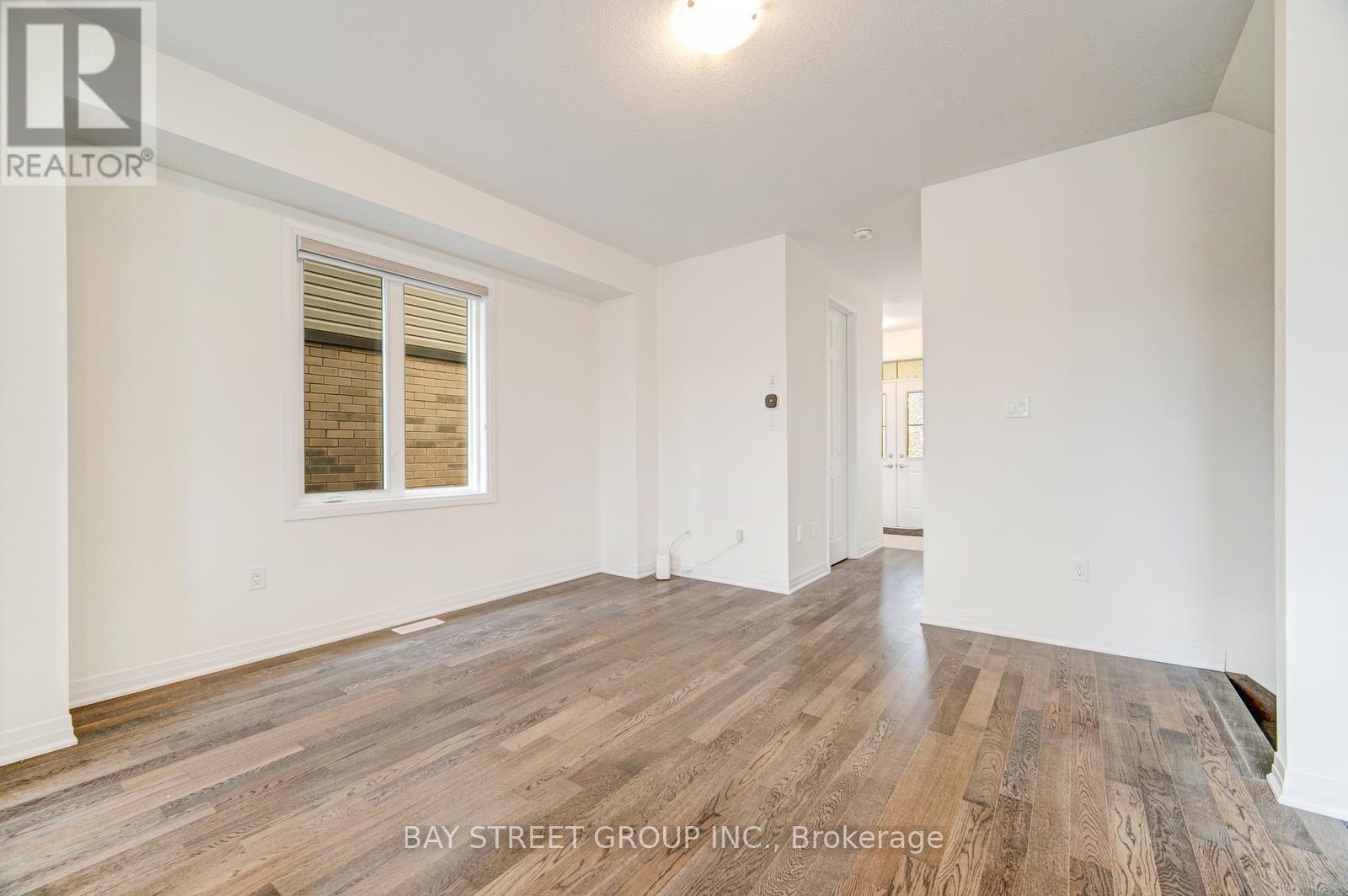 A spacious room with wooden flooring and white walls, part of a Bay Street Group Inc. property in Brokerage.