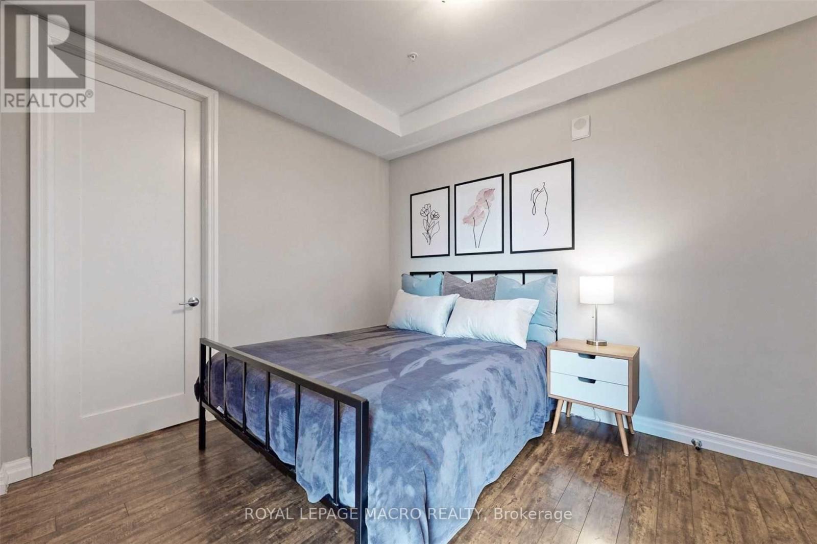 A bedroom with a bed, nightstand, and pictures on the wall.