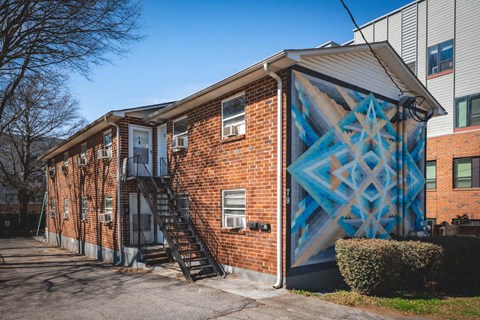 A brick building with a blue geometric mural on the side.