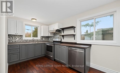 A kitchen with a stainless steel dishwasher and wooden floors.