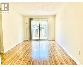 A spacious room with wooden floors and a sliding glass door leading outside.