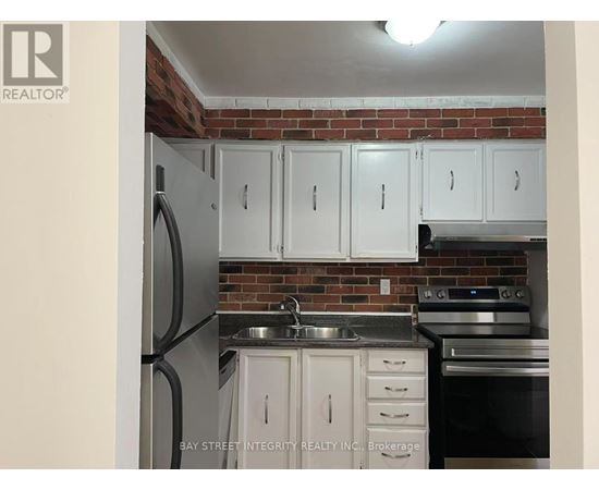 A kitchen with white cabinets and a brick wall.