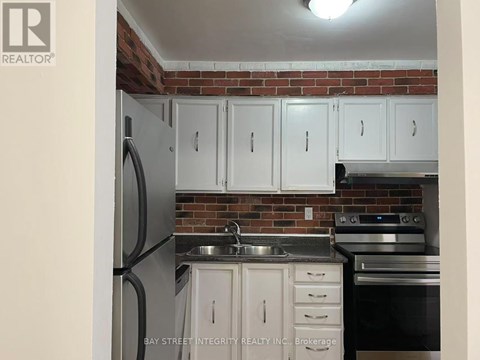A kitchen with white cabinets and a brick wall.