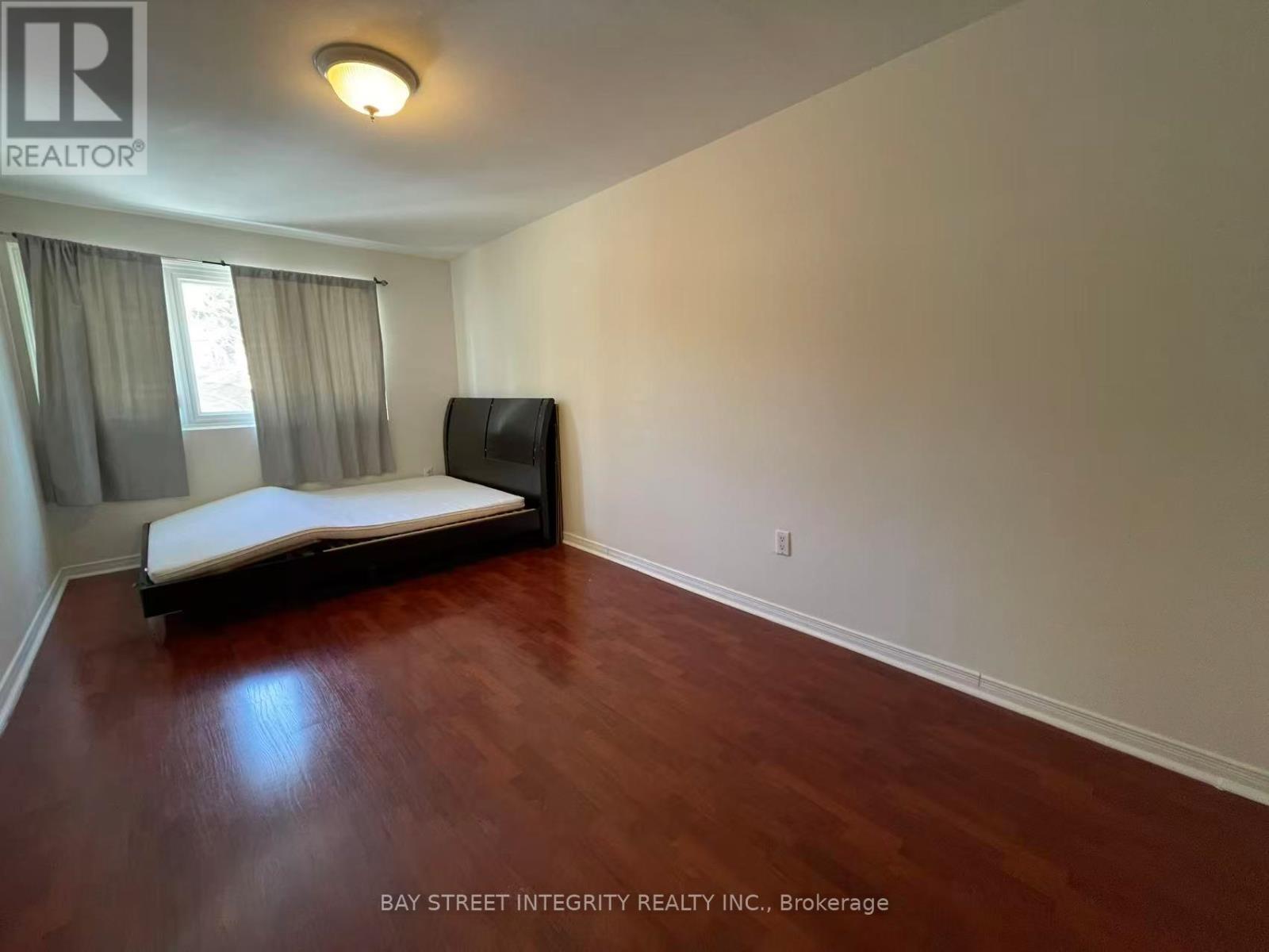 A bedroom with a bed, a television, and a window with curtains.