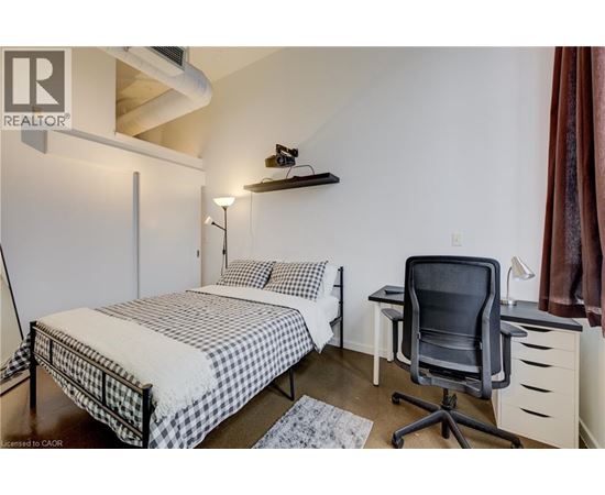 A bedroom with a bed, desk, and chair.