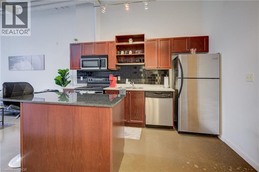 A kitchen with a refrigerator, microwave, oven, and sink.
