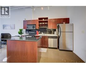 A kitchen with a refrigerator, microwave, oven, and sink.