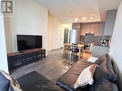 A living room with a black leather couch and a flat screen TV.
