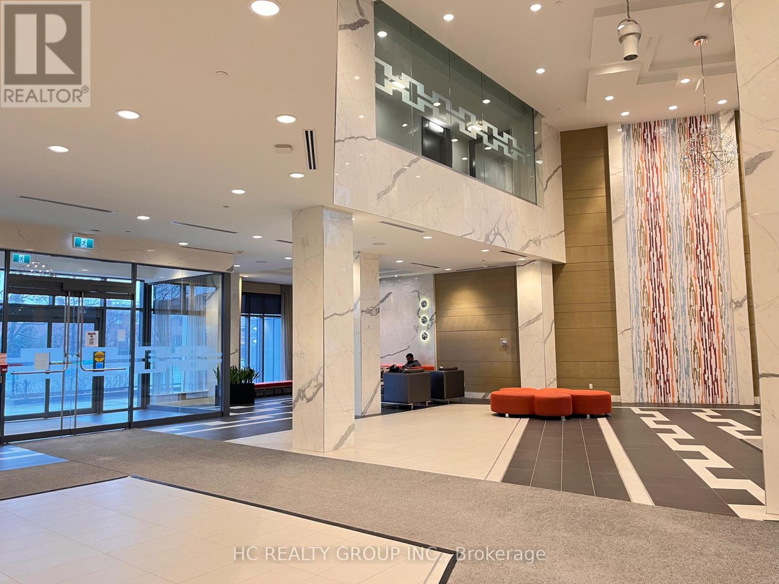 The lobby of a building with a glass wall and a red couch.