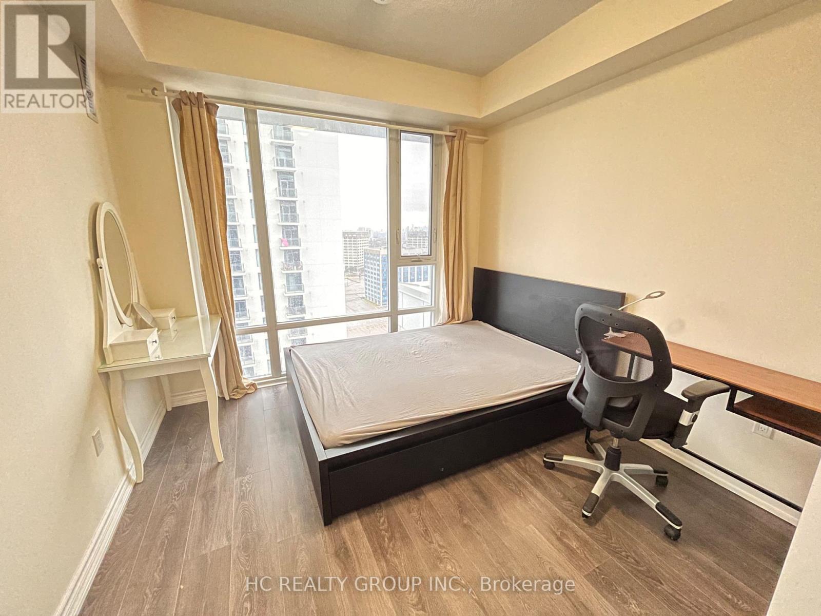 A bedroom with a bed, desk, and chair.