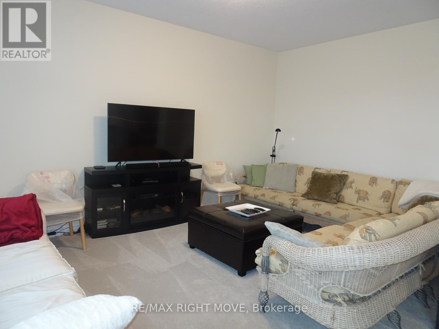 A living room with a white couch, a black entertainment center, and a television.