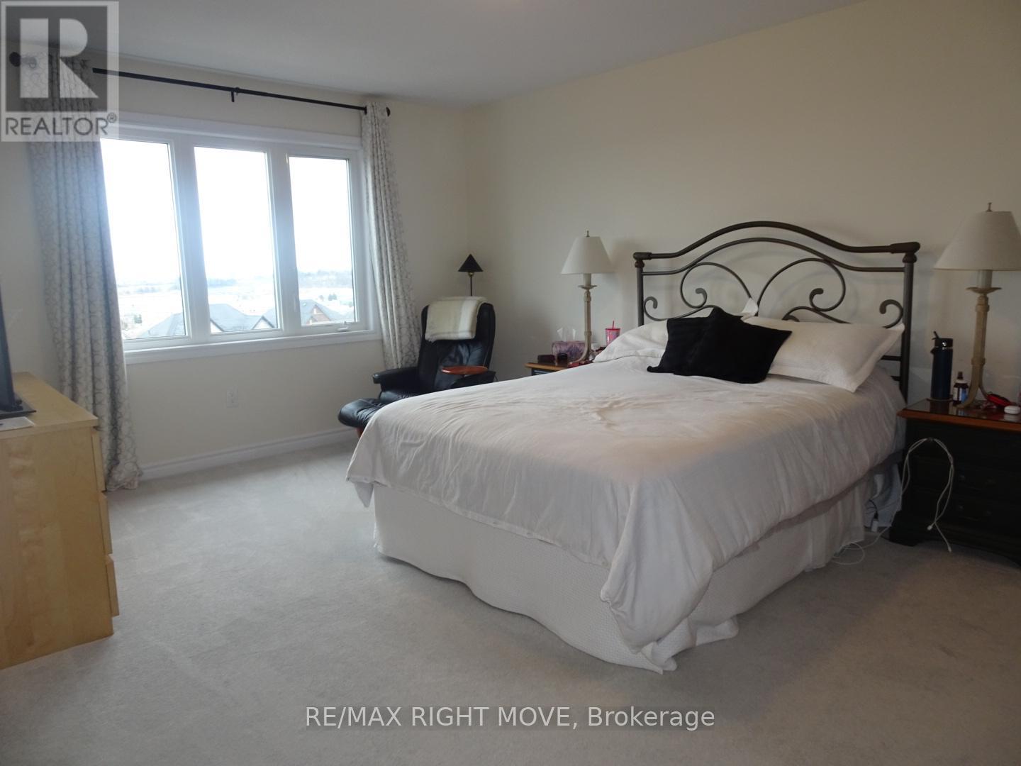 A bedroom with a large bed and a window with curtains.