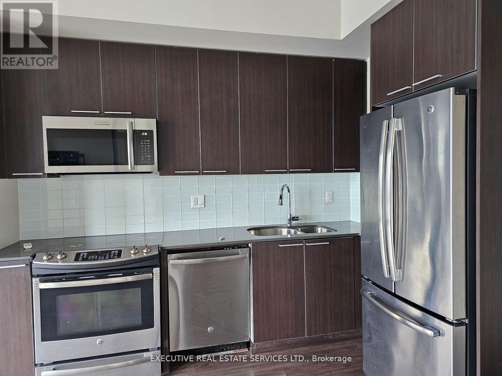 A kitchen with brown cabinets and stainless steel appliances.