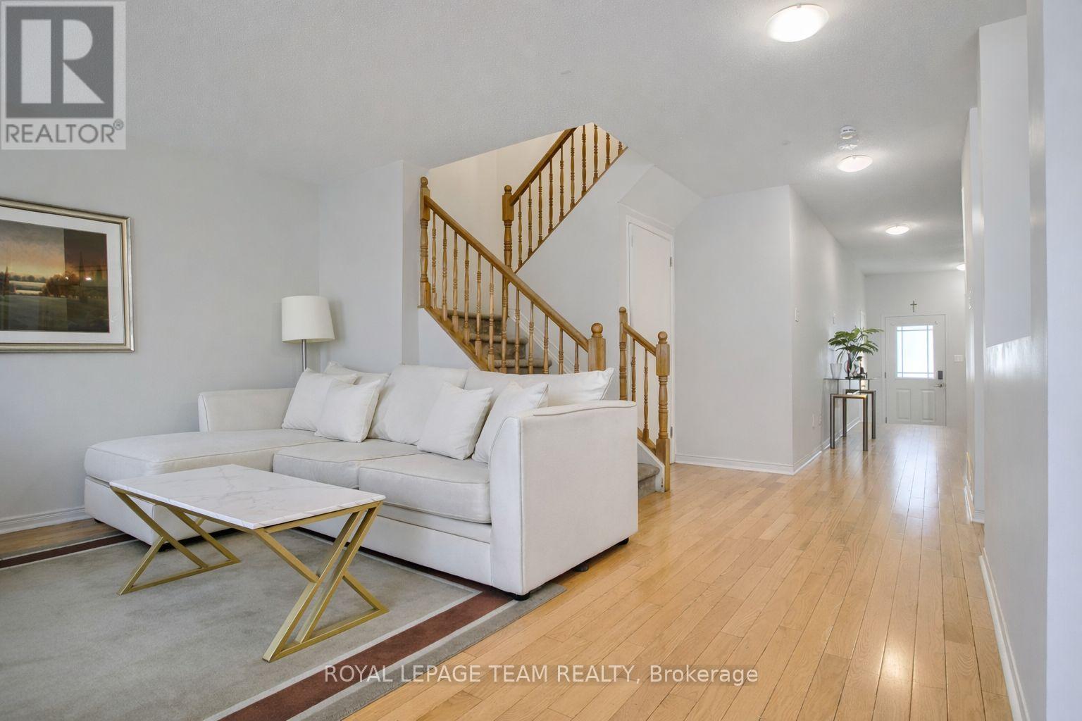 A living room with a white couch and a wooden staircase.