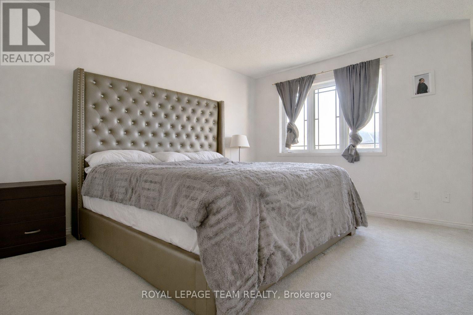 A bedroom with a large bed and a window with curtains.
