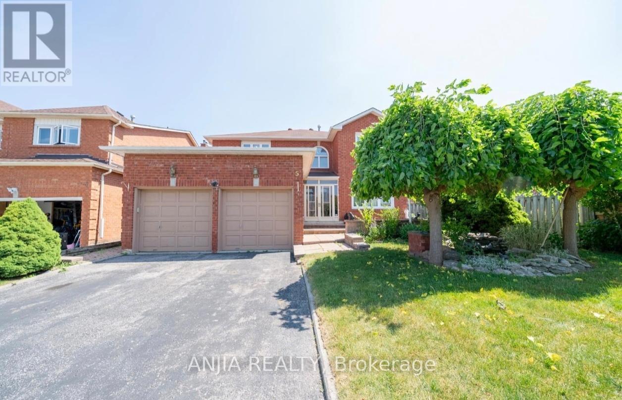 A house with a driveway and a tree in front of it.