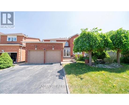 A house with a driveway and a tree in front of it.