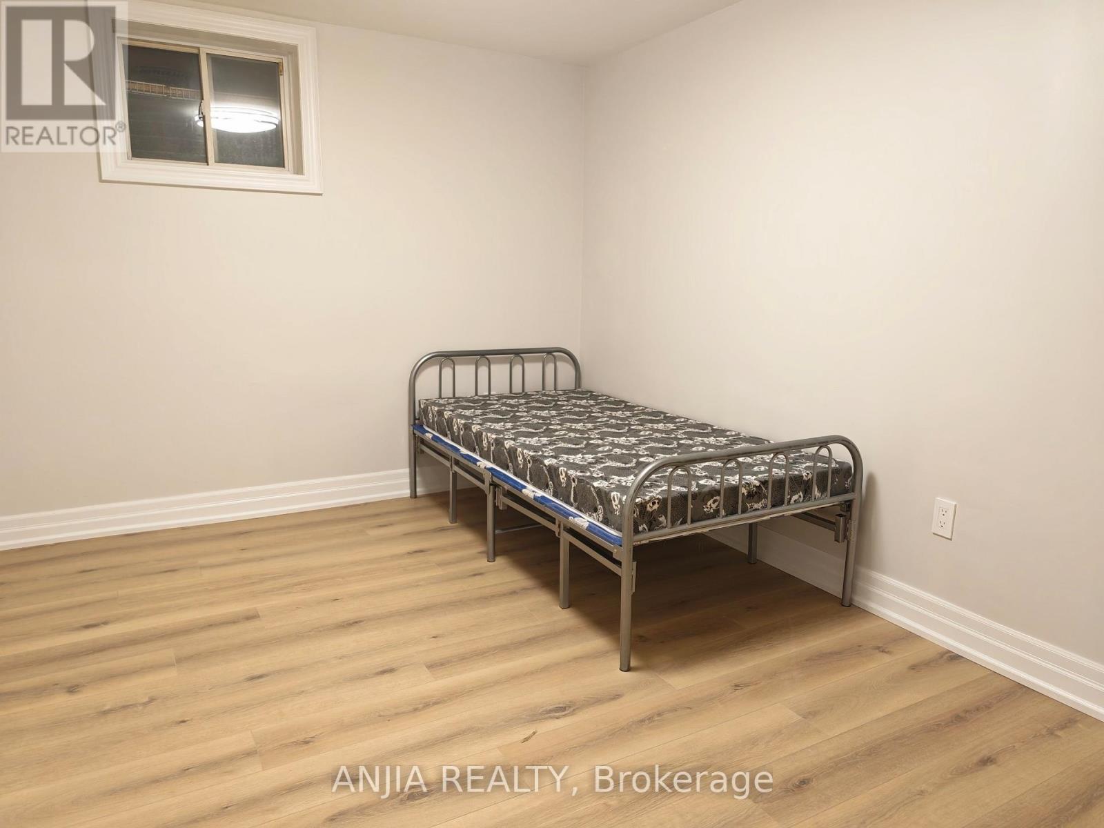 A bedroom with a bed and wooden flooring.