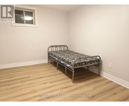 A bedroom with a bed and wooden flooring.