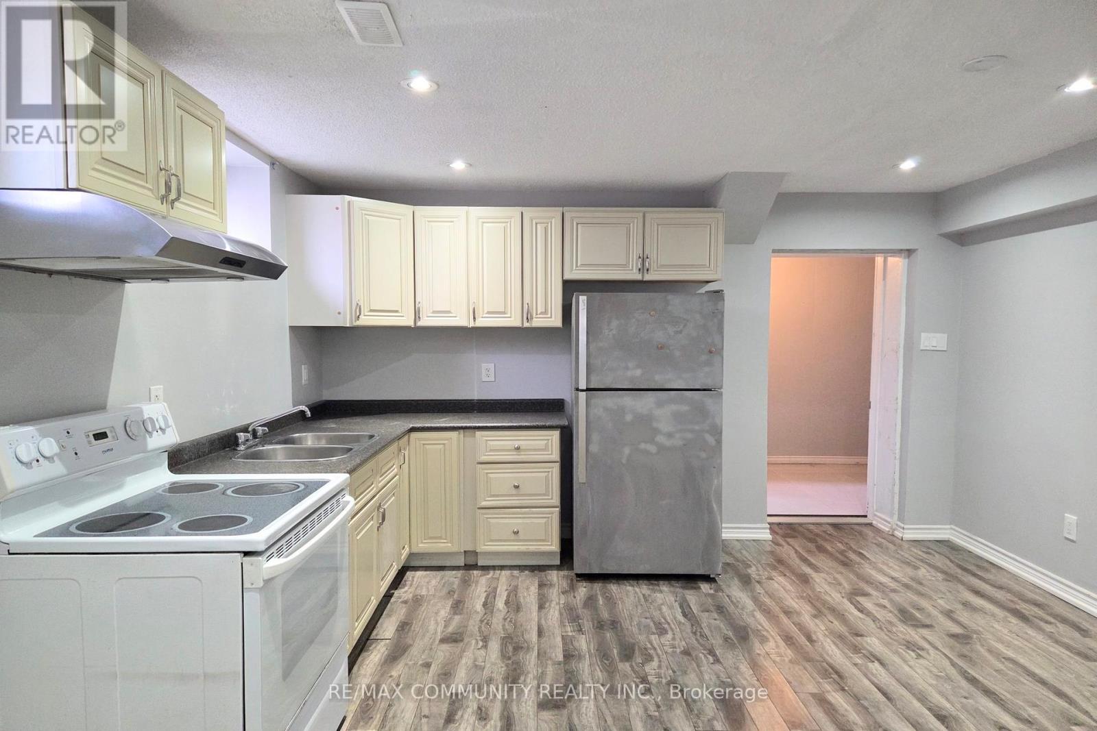 A kitchen with a stove top oven, refrigerator, and cabinets.