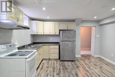 A kitchen with a stove top oven, refrigerator, and cabinets.
