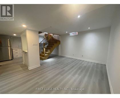 A spacious room with a staircase and a kitchen area.