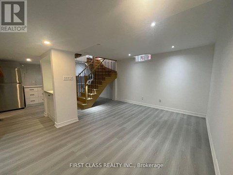 A spacious room with a staircase and a kitchen area.