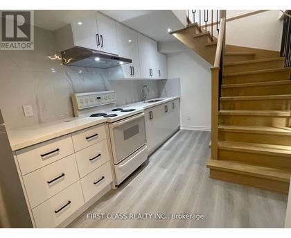 A modern kitchen with a stainless steel oven and wooden staircase.