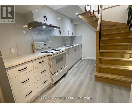 A modern kitchen with a stainless steel oven and wooden staircase.