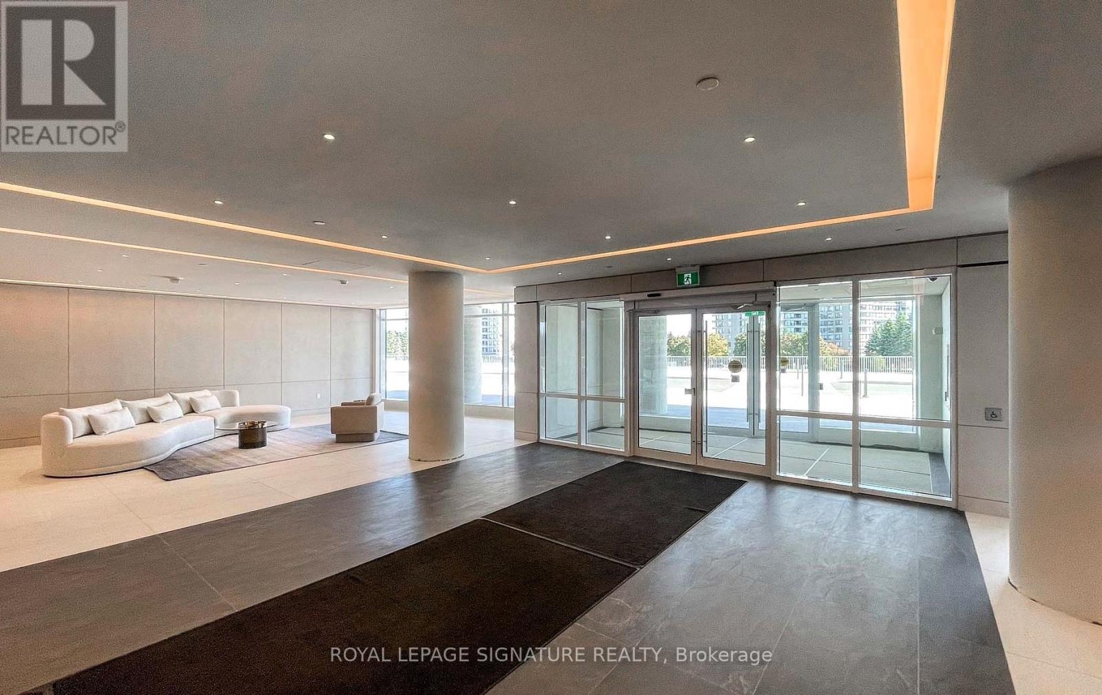 A spacious lobby area with a black carpet and a white sofa.