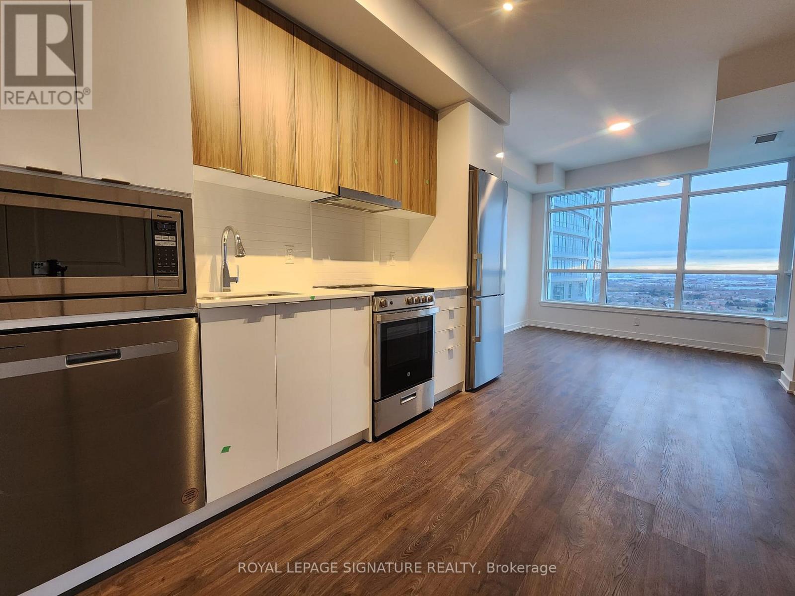 A well-lit kitchen with wooden floors and stainless steel appliances.