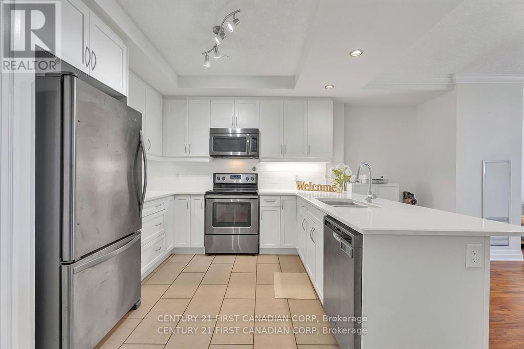 A kitchen with white cabinets and a stainless steel refrigerator.
