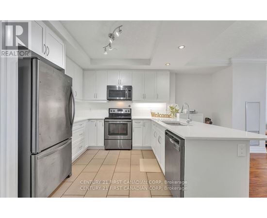 A kitchen with white cabinets and a stainless steel refrigerator.