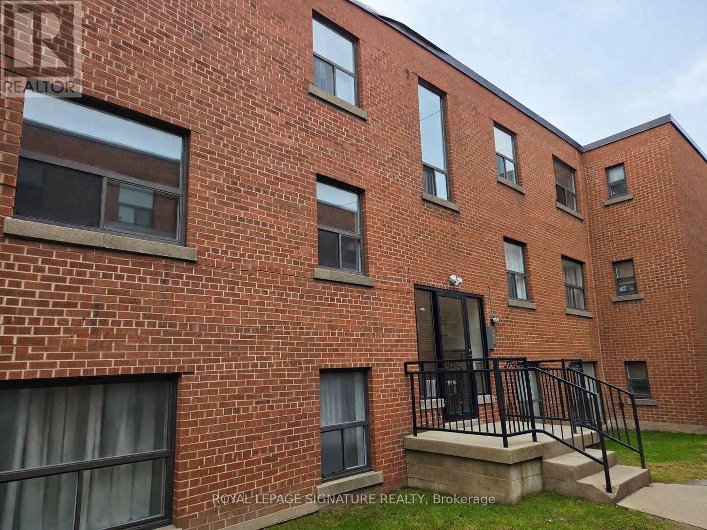 A red brick building with a black railing in front.