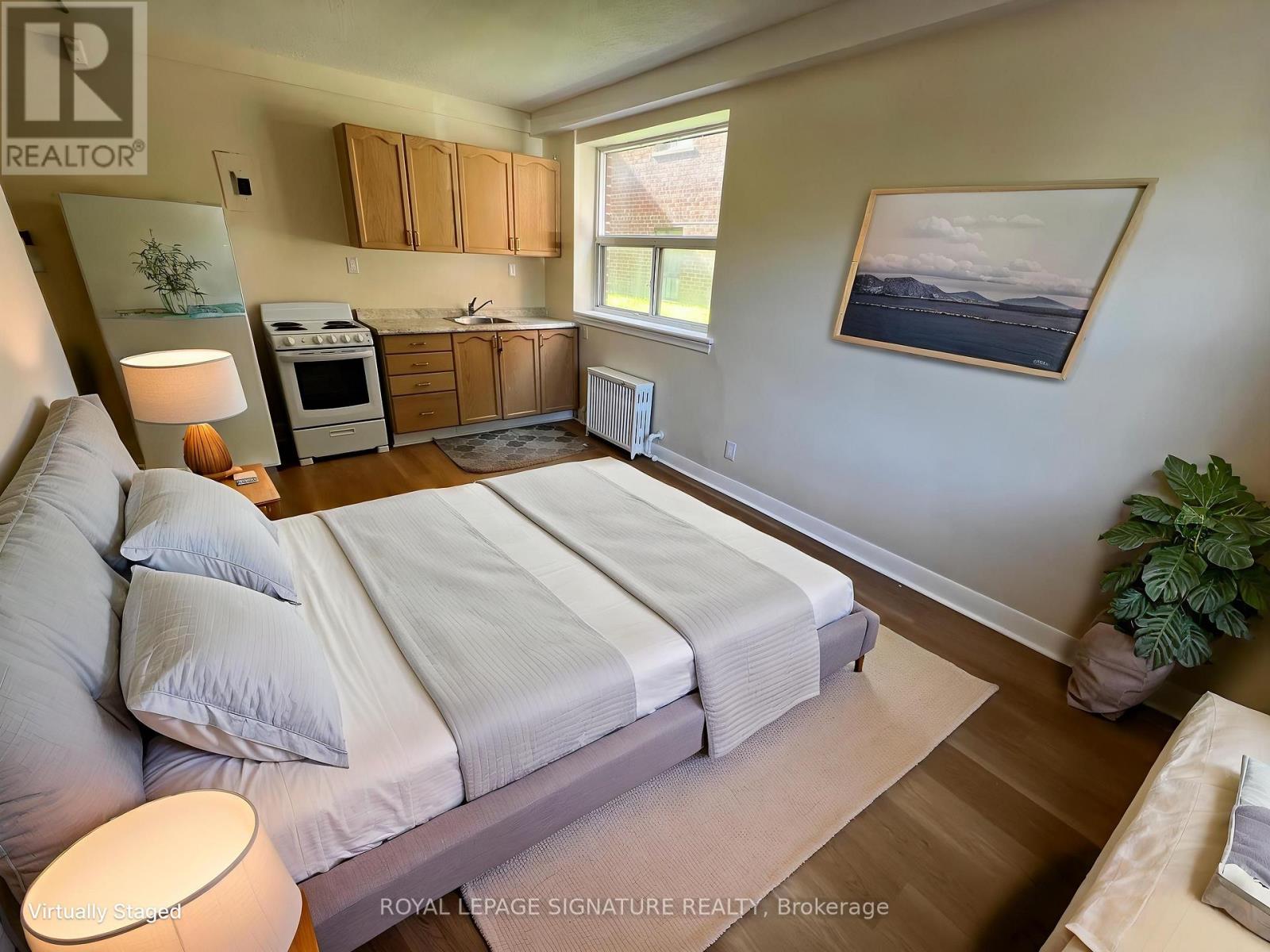A bedroom with a large bed and a painting on the wall.