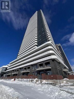 A tall building with a curved top is under construction with snow on the ground.