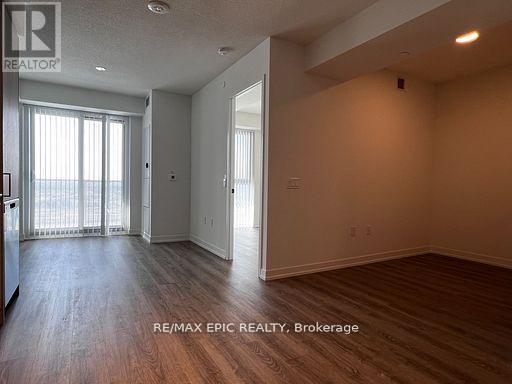 A spacious room with wood flooring and a sliding glass door leading to a balcony.