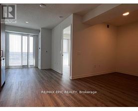 A spacious room with wood flooring and a sliding glass door leading to a balcony.