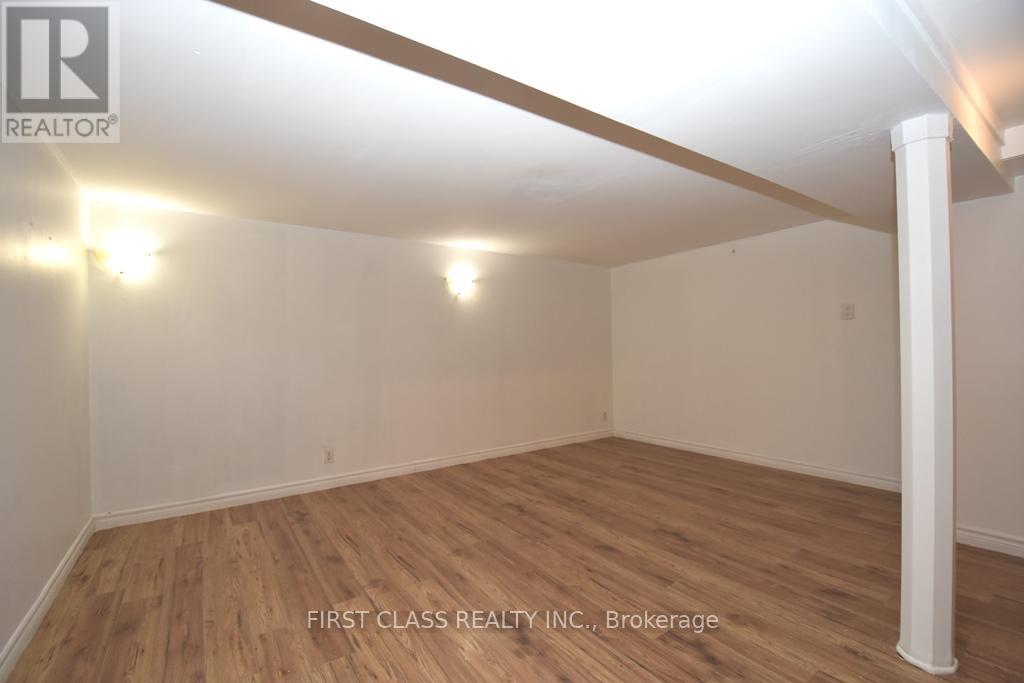 A room with wooden flooring and white walls, with a light fixture on the ceiling.