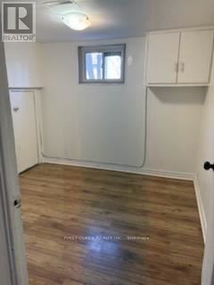 A room with wooden flooring and white walls, with a light fixture on the ceiling.