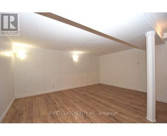 A room with wooden flooring and white walls, with a light fixture on the ceiling.