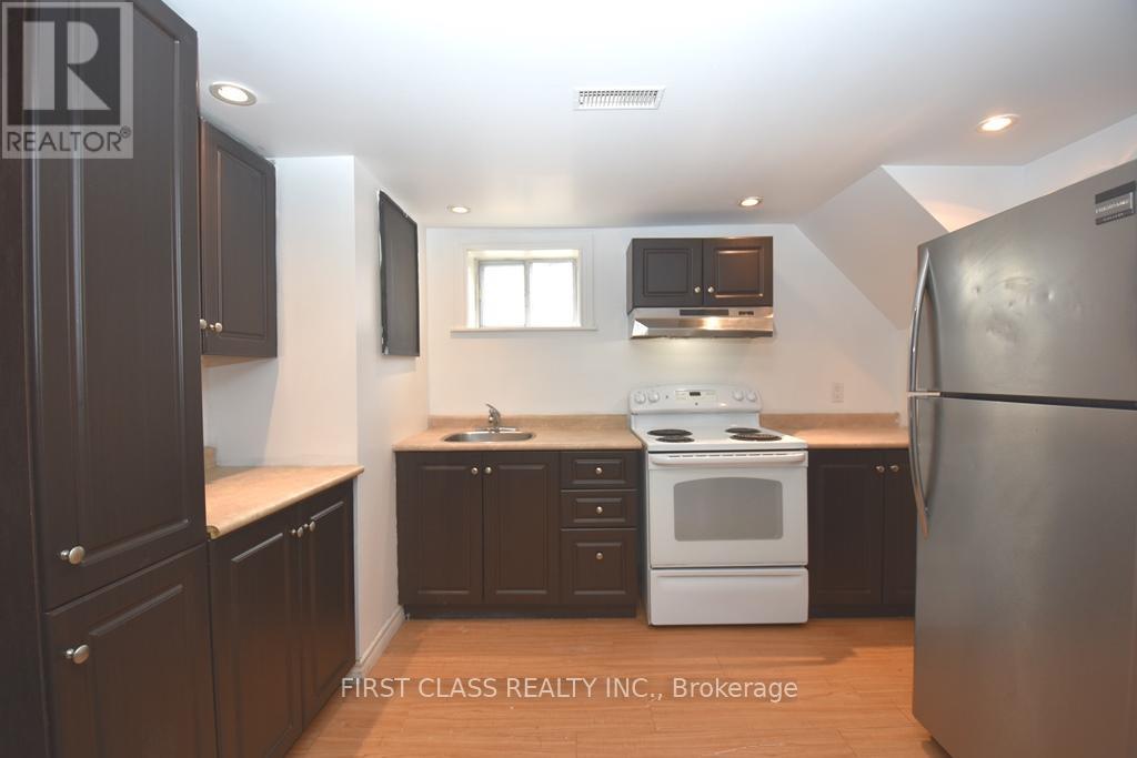 A kitchen with dark brown cabinets and a white stove top oven.